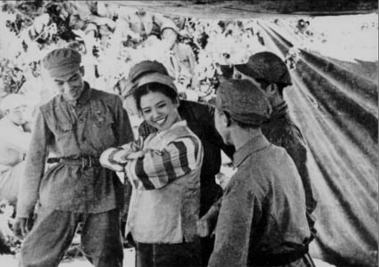 1952年8月，志愿军第12军文工团分成若干个小组，每个成员都要求“一专多能”，到前沿阵地为部队演出。图为小分队表演的朝鲜舞《志愿军与朝鲜小孩》（拉块雨布作舞台）