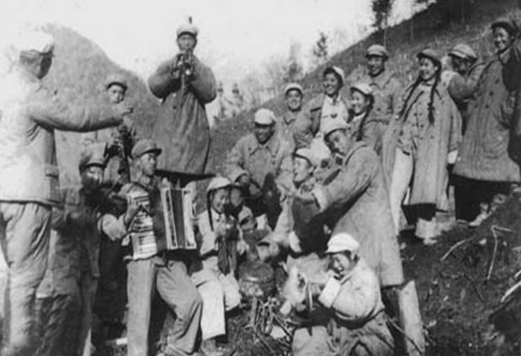1952年11月，志愿军第12军深入到前沿阵地的文工团员与战士们利用战斗间隙在山坡上联欢。