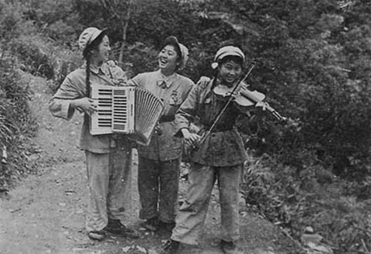 1952年8月，志愿军第12军文工团分成若干个小组，每个成员都要求“一专多能”，到前沿阵地为部队演出。图为她们在坑道外拉琴唱歌。