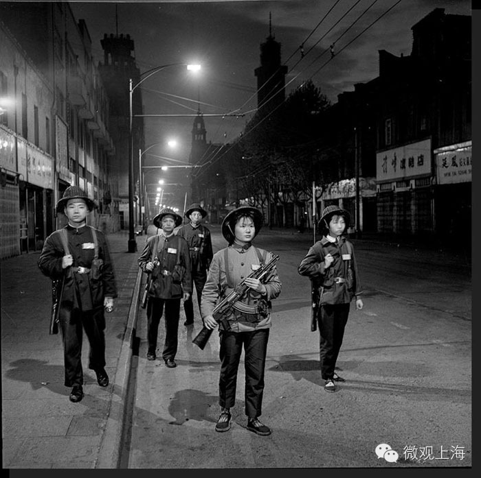 1975年4月25日夜，市百一店民兵在南京路上巡逻。当年有这样一个民兵群体：一身工装，头戴柳条安全帽，肩背钢枪，无论女民兵男民兵都精神抖擞，他们穿梭在上海的大街小巷，守护着这座城市的安全